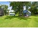 Exterior view of blue shed with a covered porch with a green lawn with mature trees at 3229 Gardner Oaks Ln, Lakeland, FL 33810