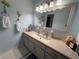 Bathroom featuring double vanity, light blue walls, and tropical-themed decor, creating a serene atmosphere at 17569 Se 107Th Ct, Summerfield, FL 34491