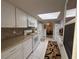 Galley kitchen with white cabinets, tiled backsplash, stainless steel appliances, and tile floors at 17569 Se 107Th Ct, Summerfield, FL 34491