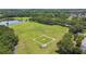 Aerial view of a baseball diamond, soccer fields, and pond in a lush, green community space at 297 Beacon Pointe Dr, Ocoee, FL 34761