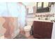 Well-lit bathroom with colorful shower curtain, sink with vanity, and overhead storage space at 5 Moonlight Ln, Winter Haven, FL 33884
