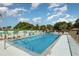 Community swimming pool surrounded by lounge chairs and green trees under a blue sky at 89 Fremont Ave # 504, Daytona Beach, FL 32114