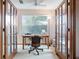 Bright home office featuring French doors, a large window with blinds, and a comfortable workspace at 508 Alcazar Ct, Lady Lake, FL 32159