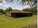 View of the backyard featuring a large screened-in porch, and lush landscaping at 21590 Sw 84Th Loop, Dunnellon, FL 34431