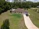 Aerial view showcasing a single-Gathering home with an attached garage, expansive lawn, and a long driveway at 21590 Sw 84Th Loop, Dunnellon, FL 34431