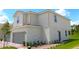 Side view of a two-story home featuring a two-car garage, manicured landscaping and a red brick walkway at 584 Bay Leaf Dr, Poinciana, FL 34759