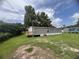 A side view of the home with trees, a wooden deck, and a blue sky at 2777 Cr 673, Bushnell, FL 33513