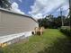 Siding of a home with green lawn, blue hose, and wooden stairs visible at 2777 Cr 673, Bushnell, FL 33513