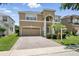 Inviting two-story tan home featuring a paved driveway, well-kept lawn, and a classic two-car garage at 5233 Los Palma Vista Dr, Orlando, FL 32837