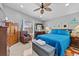 Cozy bedroom with a blue comforter, wood dresser, ceiling fan, and a plush chair, offering comfort and style at 1955 Manatee Ct, Kissimmee, FL 34759