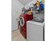 Functional laundry room featuring a red washing machine and white dryer at 1955 Manatee Ct, Kissimmee, FL 34759