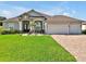 Charming home featuring a manicured lawn, paver driveway, and a three-car garage at 3544 Lakeside Heritage Dr, Lakeland, FL 33812