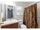 Bathroom with large mirror, sink, toilet, and shower with decorative brown curtain at 4132 Festival Pointe Blvd, Mulberry, FL 33860