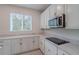 Kitchen featuring white cabinetry, granite countertops, and stainless steel microwave over black cooktop at 16398 Yelloweyed Dr, Clermont, FL 34714