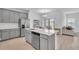 Open concept kitchen and dining area featuring stainless steel appliances, gray cabinets, and quartz countertops with a breakfast bar at 2359 White Cedar Way, Haines City, FL 33844