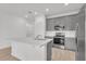 Modern kitchen features stainless steel appliances, gray cabinets, an island with quartz countertops, and an undermount sink at 2359 White Cedar Way, Haines City, FL 33844