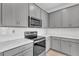 A well-lit kitchen features stainless steel appliances, gray cabinets, subway tile backsplash, and sleek countertops at 2359 White Cedar Way, Haines City, FL 33844