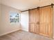 Bedroom with rustic sliding doors, a window and neutral carpet at 10084 Moss Rose Way, Orlando, FL 32832