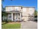 Two-story tan house features a well-manicured lawn, columns, and a three-car garage at 10084 Moss Rose Way, Orlando, FL 32832
