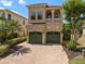 Two-story tan home with a two-car garage, balcony, and lush landscaping at 852 Desert Mountain Ct, Reunion, FL 34747