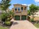 Two-story tan home with a two-car garage, balcony, and lush landscaping at 852 Desert Mountain Ct, Reunion, FL 34747