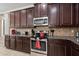 Close up on a kitchen with dark cabinets, granite countertops, and stainless steel appliances at 852 Desert Mountain Ct, Reunion, FL 34747