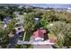 Aerial view of a white single-Gathering home featuring a red roof and spacious yard, surrounded by lush greenery at 1938 E Fern Rd, Lakeland, FL 33801
