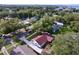 An aerial view of a single-Gathering home with a red roof, featuring a well-maintained yard and mature trees at 1938 E Fern Rd, Lakeland, FL 33801