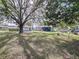 Large backyard with mature trees, a grassy area, and a partially fenced perimeter at 1938 E Fern Rd, Lakeland, FL 33801