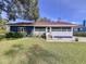 A quaint blue home with a well-manicured lawn and flowering bushes at 1938 E Fern Rd, Lakeland, FL 33801
