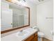 Bathroom with mirror over sink, toilet, towel rack and shower with glass door at 818 Cherry Laurel St, Minneola, FL 34715