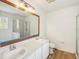 Bathroom with double sink vanity, toilet, shower with glass door, large mirror and modern flooring at 818 Cherry Laurel St, Minneola, FL 34715
