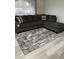 Living room featuring a gray sectional sofa and a stylish gray patterned rug on light wood floors at 204 Madison St, Minneola, FL 34715