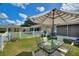 Grassy backyard with a table and chairs under a striped umbrella at 4711 Club Cir, Lakeshore, FL 33854