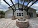 Backyard patio featuring a custom brick fire pit, covered by a pergola, with a view of the home's exterior at 13774 Meadowpark Ave, Orlando, FL 32826
