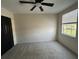Bedroom features plush carpet, a ceiling fan, and closet with a view from the window at 13774 Meadowpark Ave, Orlando, FL 32826