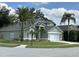 Charming light green home with lush landscaping, palm trees, and a two-car garage at 13774 Meadowpark Ave, Orlando, FL 32826