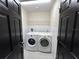 Laundry room with washer, dryer, shelving, and tiled walls provides functionality at 13774 Meadowpark Ave, Orlando, FL 32826
