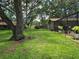 Expansive backyard with lush green grass, mature trees, and partial view of the home's exterior at 909 Heatherbrook Dr, Auburndale, FL 33823