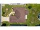 Aerial view of the well-maintained home with a brown roof, green lawn, and long driveway at 1032 Kelsea Cir, The Villages, FL 32159