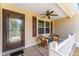 Cozy covered porch with two wicker chairs and a small table, perfect for relaxing, and a decorative glass front door at 1032 Kelsea Cir, The Villages, FL 32159