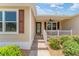 Inviting front porch with railing and ceiling fan provides a cozy outdoor space with decorative shrubs and well kept garden at 1032 Kelsea Cir, The Villages, FL 32159
