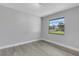 Bedroom featuring new gray wood-look flooring with view out a large window at 2151 Groveglen S Ln, Lakeland, FL 33813
