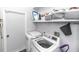 Functional laundry room with white washer and dryer, storage shelves, and door at 2423 Turnberry Dr, Oviedo, FL 32765