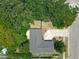 An aerial view of a single story home with a dark roof surrounded by mature trees and cracked driveway at 3300 Glen Village Ct, Orlando, FL 32822