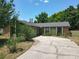 Home exterior featuring stone details, cracked driveway, manicured shrubs, and a wooden privacy fence at 3300 Glen Village Ct, Orlando, FL 32822