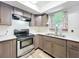 Modern kitchen with stainless steel stove, grey cabinets, white countertops, and stylish faucet under the window at 3300 Glen Village Ct, Orlando, FL 32822