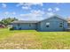 This home features a spacious backyard with a blue house, grassy lawn, and mature landscaping at 2902 Wheeler St, Bartow, FL 33830