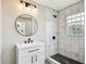 Bathroom featuring a white vanity, round mirror, and a shower with marble-look tiles and black fixtures at 2902 Wheeler St, Bartow, FL 33830