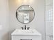 Bathroom featuring a white vanity with black hardware and a round mirror reflecting an open door at 2902 Wheeler St, Bartow, FL 33830